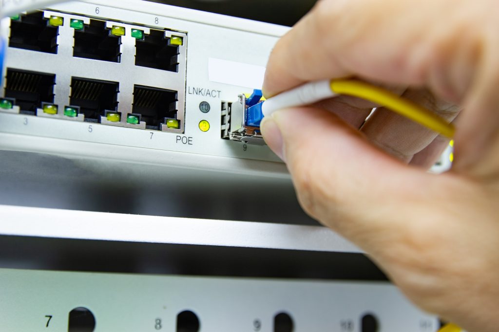 Technician connect fiber cable network to switch port in server room